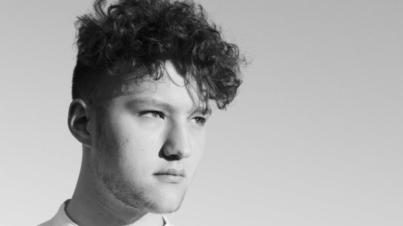 black and white shot of a man with curly hair looking afar