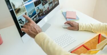 elderly man sitting by the desk and browsing on the computer