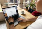 person using macbook pro on brown wooden table