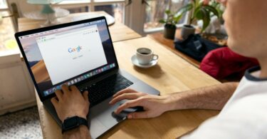 person using macbook pro on brown wooden table