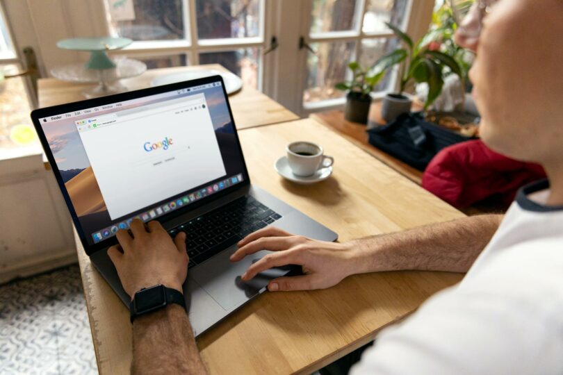 person using macbook pro on brown wooden table